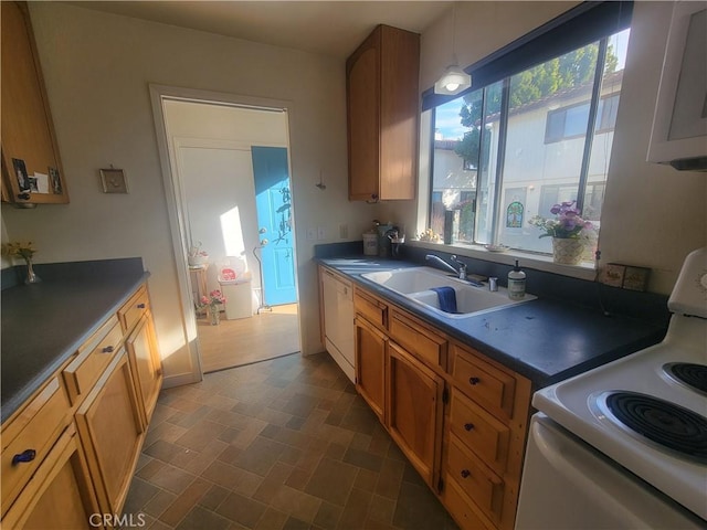 kitchen featuring dark countertops, white appliances, brown cabinetry, and a sink