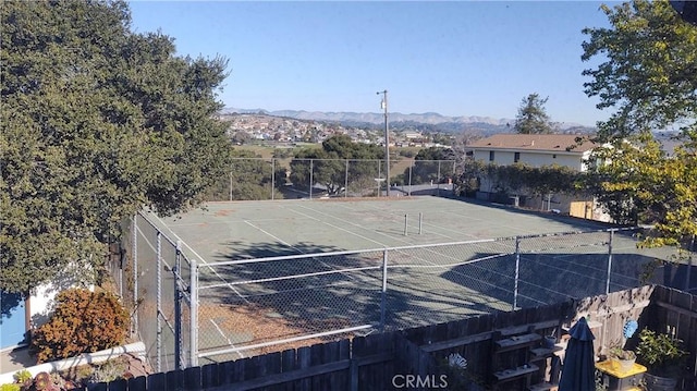 view of tennis court featuring fence and a mountain view