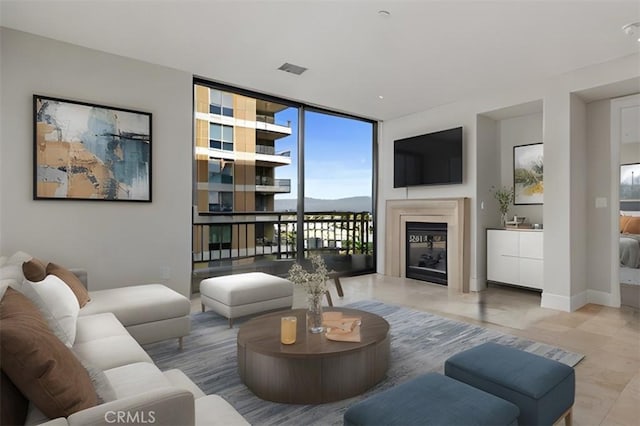 living room with a wall of windows, a glass covered fireplace, and baseboards