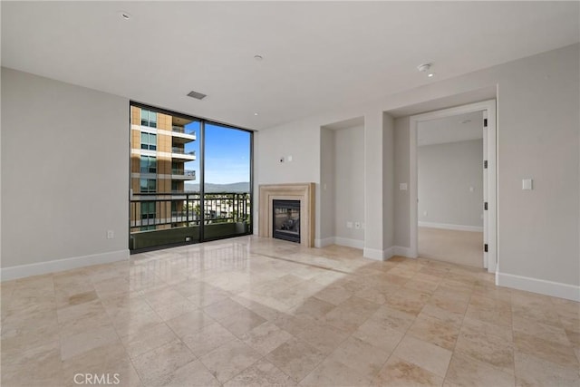 unfurnished living room featuring baseboards, a fireplace, visible vents, and floor to ceiling windows