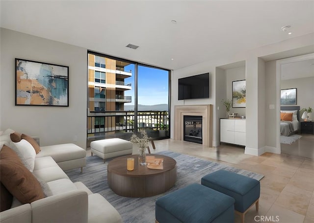 living area featuring baseboards, floor to ceiling windows, and a glass covered fireplace