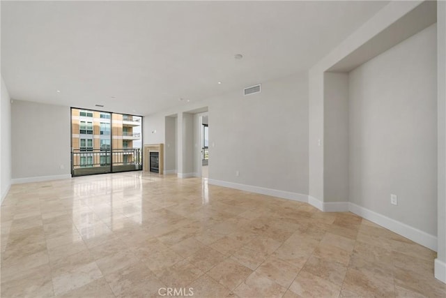 unfurnished room with baseboards, floor to ceiling windows, and visible vents