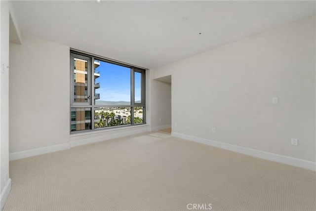 spare room featuring carpet and baseboards