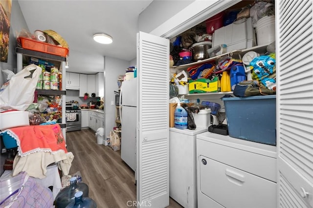 clothes washing area featuring laundry area, washer and clothes dryer, and wood finished floors