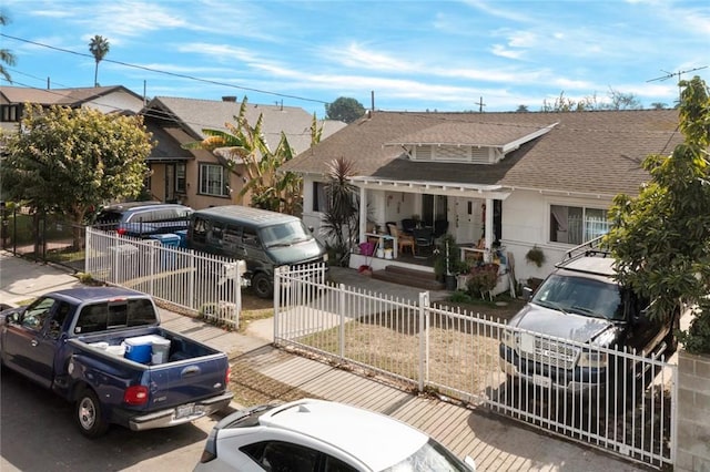 view of front of home with a fenced front yard and a shingled roof