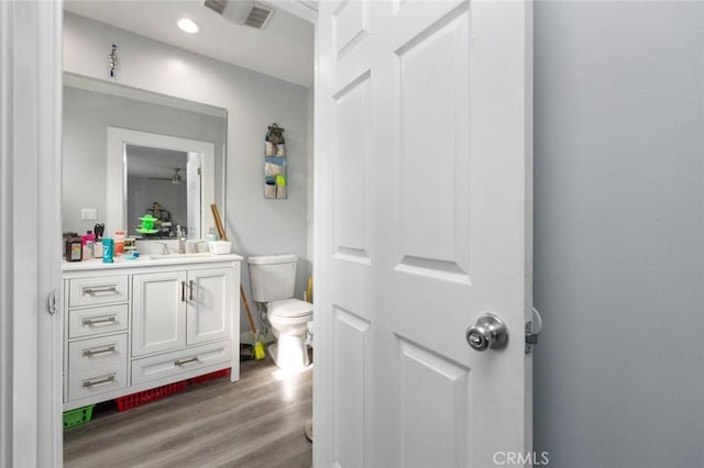 bathroom featuring visible vents, toilet, wood finished floors, vanity, and recessed lighting