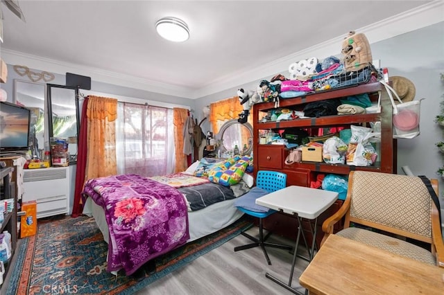 bedroom with ornamental molding and wood finished floors