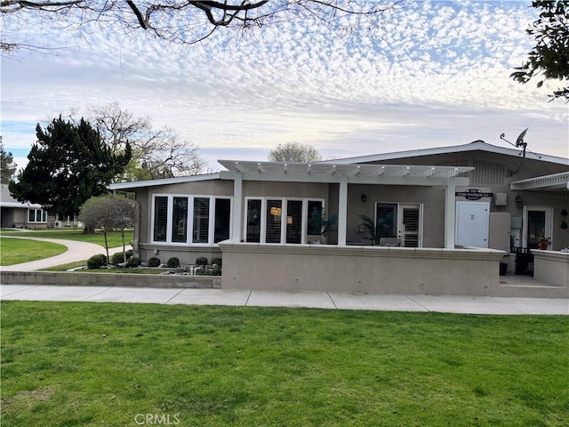 rear view of property with a lawn and stucco siding