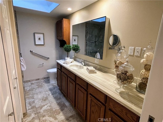 bathroom with toilet, a skylight, and vanity