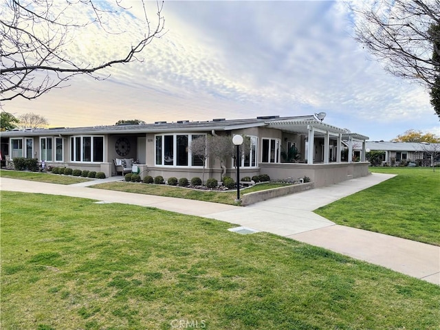 view of front facade featuring a front yard, a pergola, and stucco siding