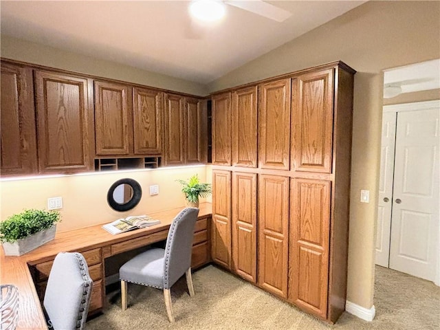 office area featuring lofted ceiling, built in study area, and light colored carpet