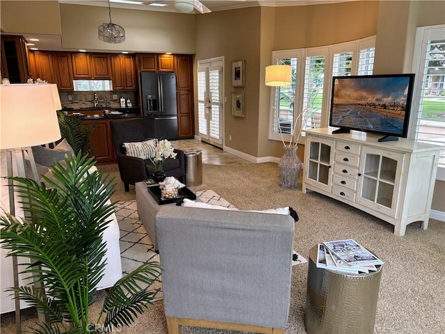 living room featuring light colored carpet, a towering ceiling, and baseboards