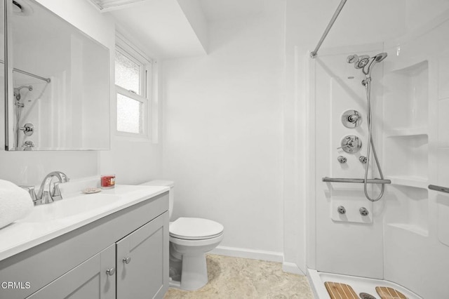 full bath featuring toilet, vanity, a shower, and baseboards