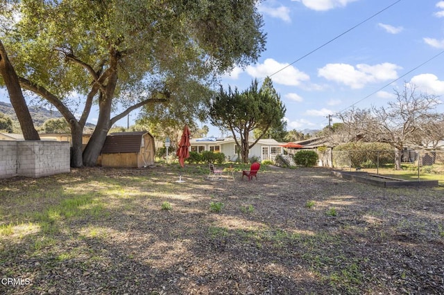 view of yard with an outdoor structure, fence, and a shed