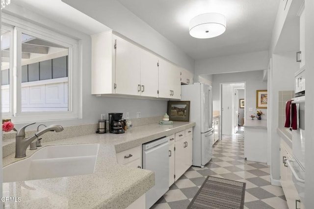 kitchen featuring a sink, white appliances, white cabinets, light countertops, and light floors