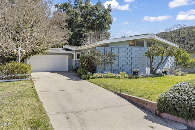 mid-century home with an attached garage, concrete block siding, concrete driveway, and a front lawn