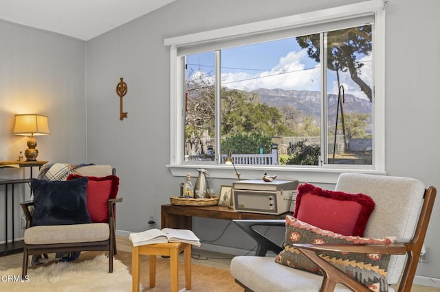 sitting room featuring a mountain view, baseboards, lofted ceiling, and wood finished floors