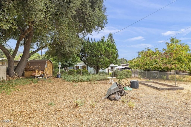 view of yard featuring an outbuilding, a storage shed, and fence