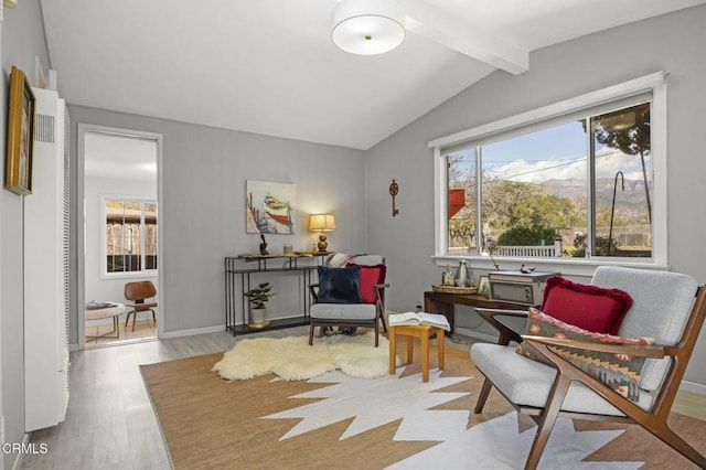 living area with baseboards, wood finished floors, and vaulted ceiling with beams