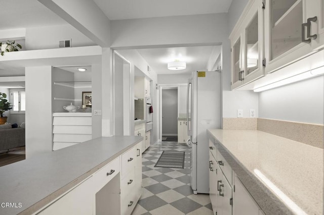 interior space featuring visible vents, light floors, light countertops, white appliances, and white cabinetry