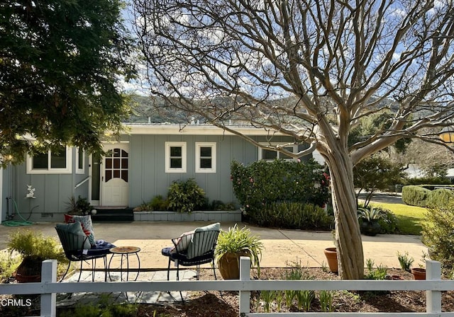 back of house with a patio, entry steps, a fenced front yard, crawl space, and board and batten siding