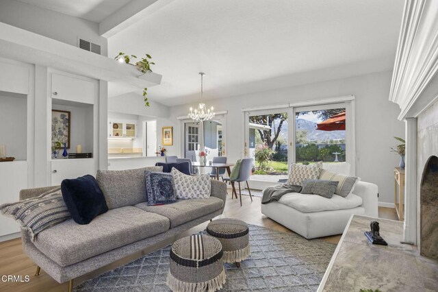 living room with a notable chandelier, visible vents, light wood-type flooring, and a premium fireplace