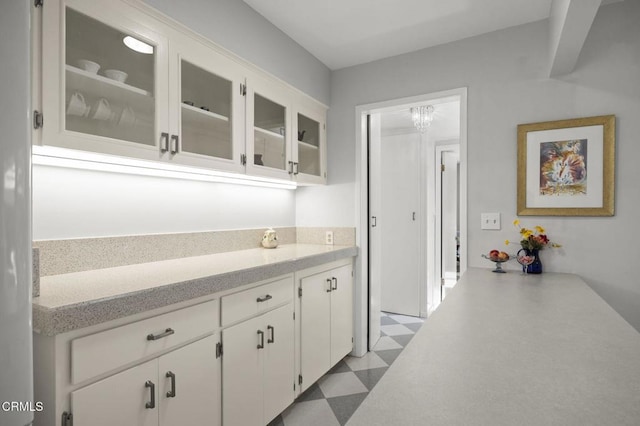 kitchen featuring white cabinetry, tile patterned floors, glass insert cabinets, and light countertops