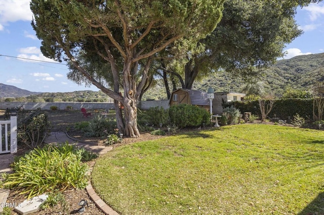 view of yard with a mountain view, an outdoor structure, and fence