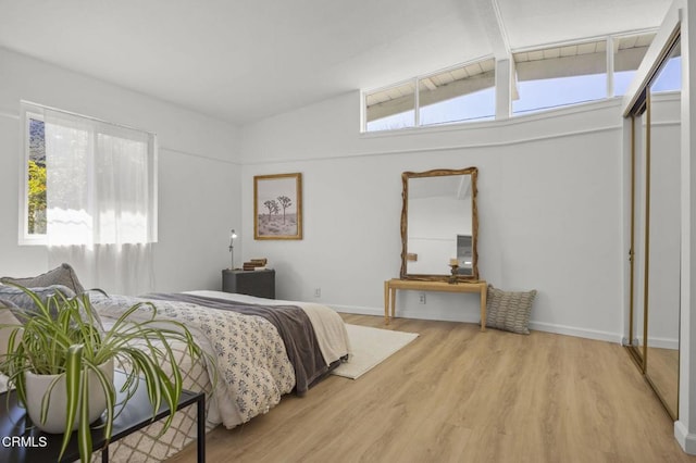 bedroom featuring multiple windows, wood finished floors, and vaulted ceiling with beams