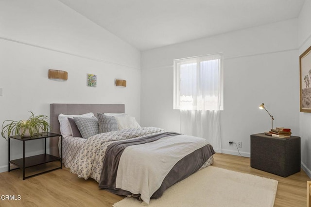 bedroom with baseboards, light wood-type flooring, and lofted ceiling