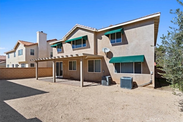 rear view of house with stucco siding, fence, a patio, and central air condition unit