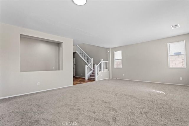 spare room featuring stairs, carpet flooring, visible vents, and baseboards