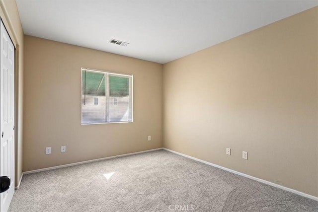 empty room with baseboards, visible vents, and carpet flooring