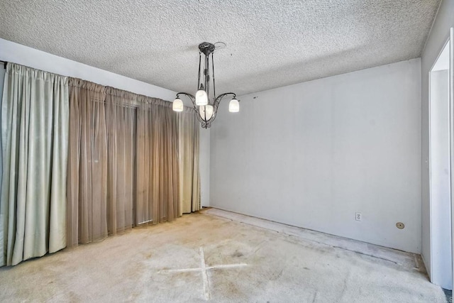 empty room featuring a notable chandelier and a textured ceiling