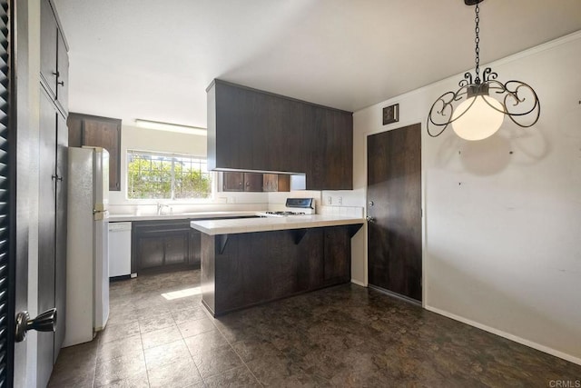 kitchen featuring white appliances, a sink, a peninsula, and dark brown cabinetry