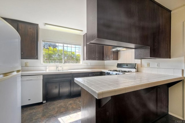 kitchen with a peninsula, white appliances, tile counters, and dark brown cabinets