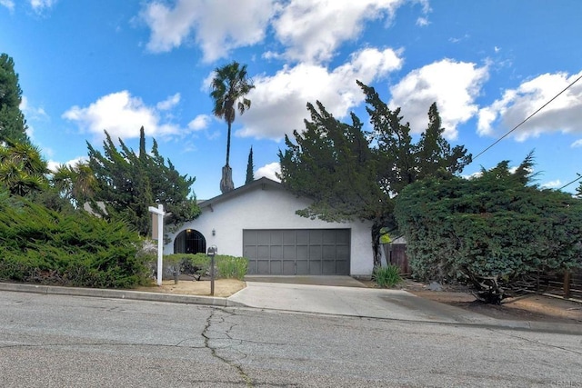 view of front of house with concrete driveway, an attached garage, and stucco siding