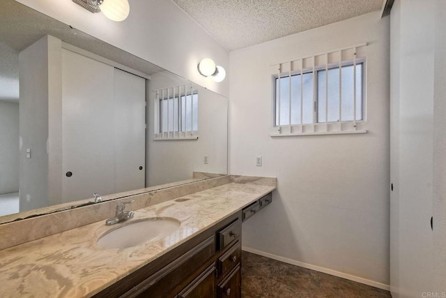 bathroom featuring baseboards, a textured ceiling, and vanity