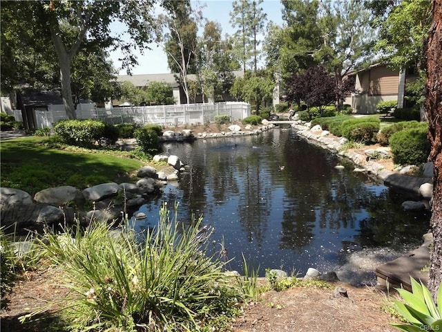 water view featuring a garden pond and fence