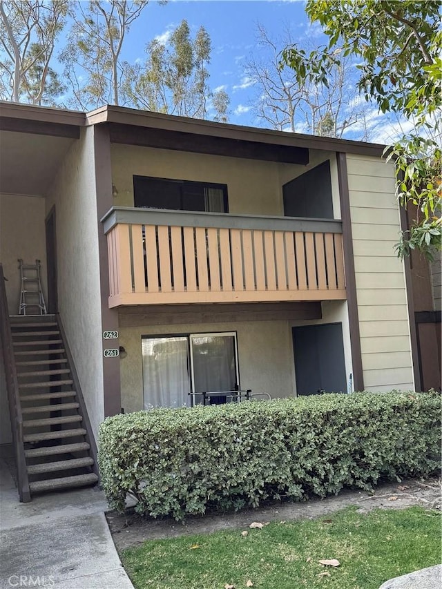 exterior space with a balcony, stairs, and stucco siding