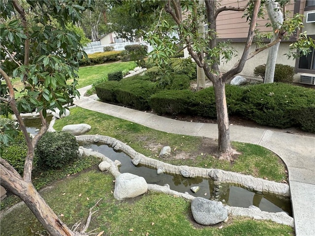 surrounding community featuring a lawn and a small pond