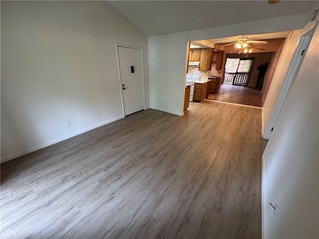 unfurnished living room with ceiling fan, baseboards, vaulted ceiling, and wood finished floors