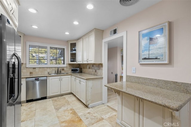 kitchen featuring visible vents, appliances with stainless steel finishes, tasteful backsplash, and a sink