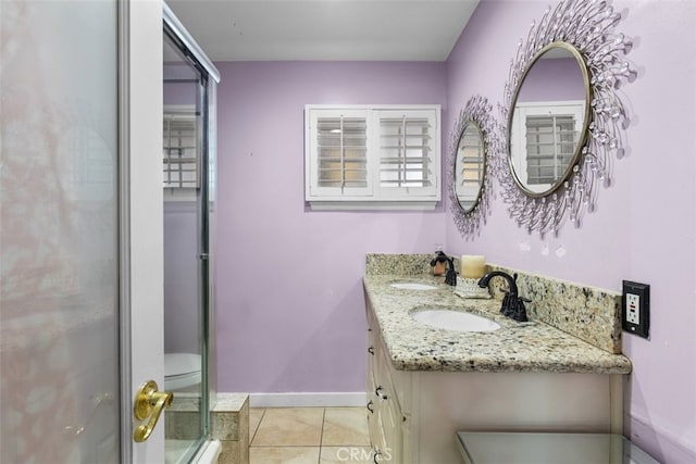 bathroom featuring baseboards, double vanity, a sink, and tile patterned floors