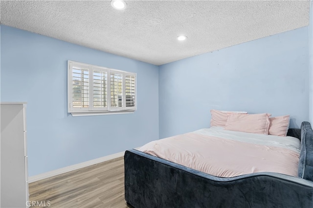 bedroom featuring a textured ceiling, recessed lighting, wood finished floors, and baseboards