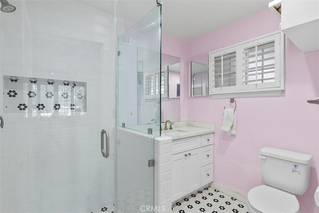 bathroom featuring vanity, a shower stall, toilet, and baseboards