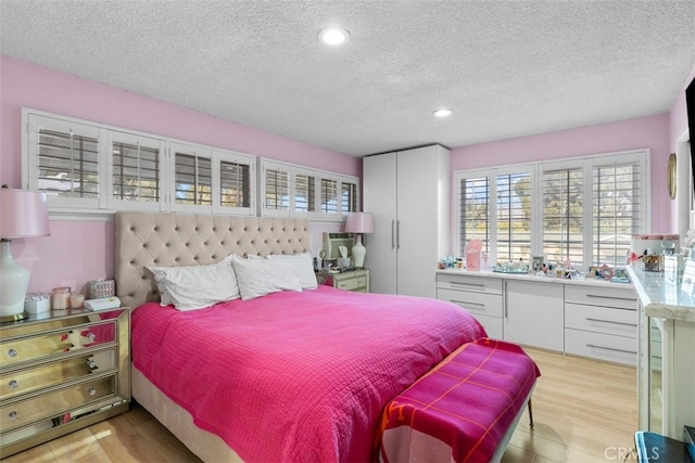 bedroom featuring light wood-type flooring, a textured ceiling, and recessed lighting