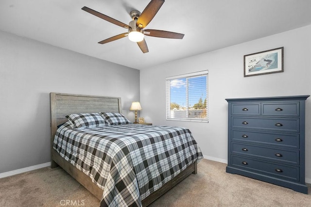 bedroom with light colored carpet, ceiling fan, and baseboards