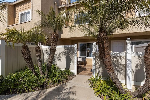 doorway to property featuring fence and stucco siding