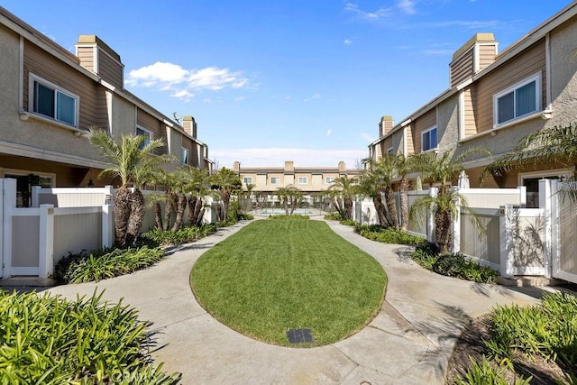 view of home's community with a yard, a residential view, and fence